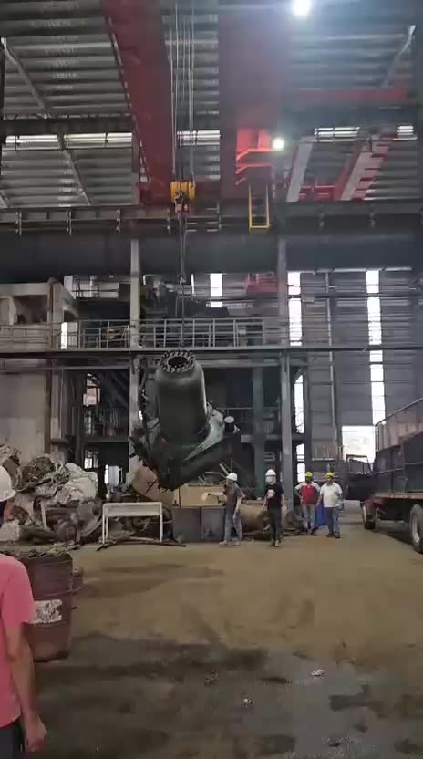 Interior de una nave industrial con puente grúa, equipo pesado y personal trabajando en el desmontaje de maquinaria.